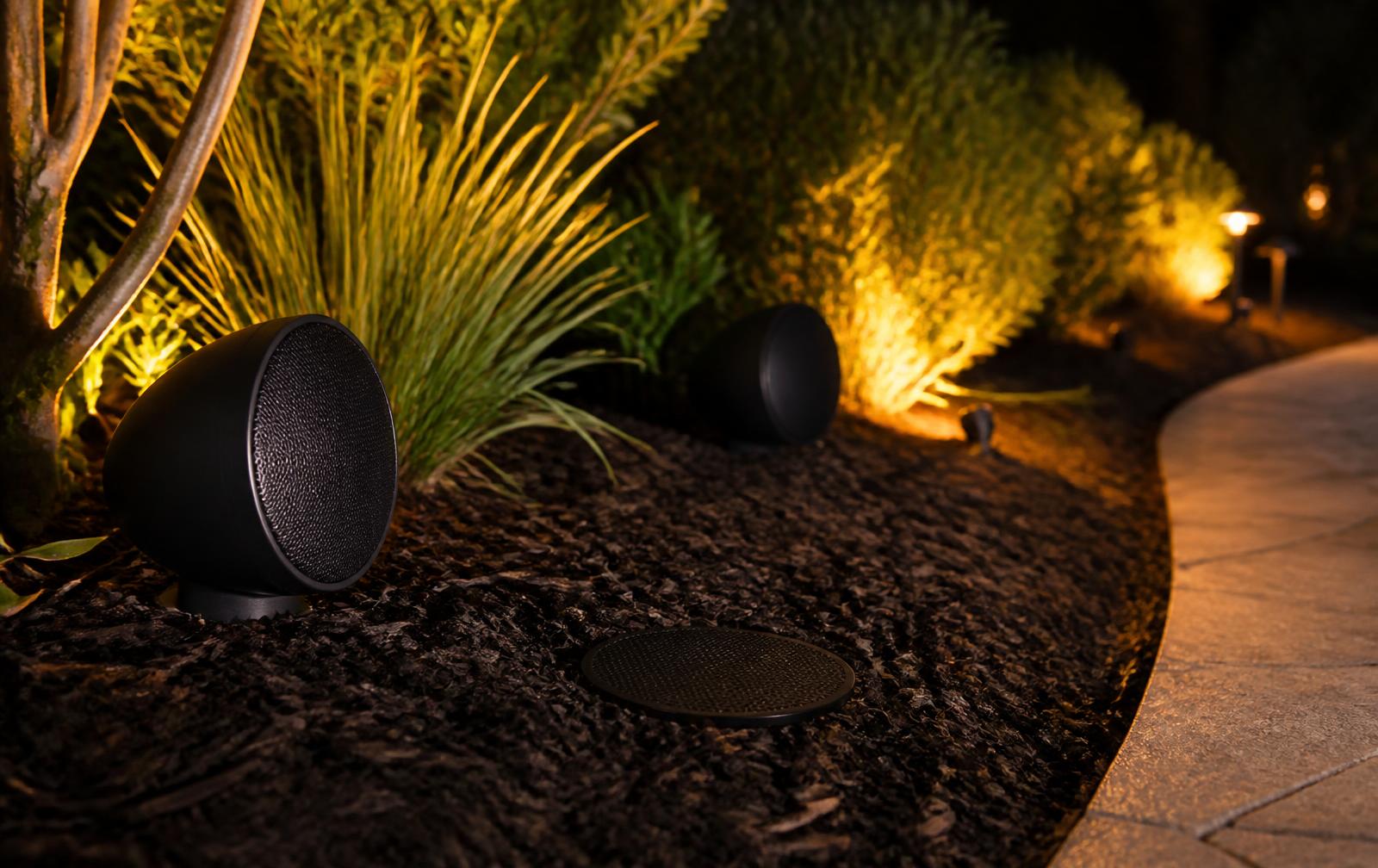 Outdoor satellite speakers and a buried subwoofer grille tucked into landscape beds