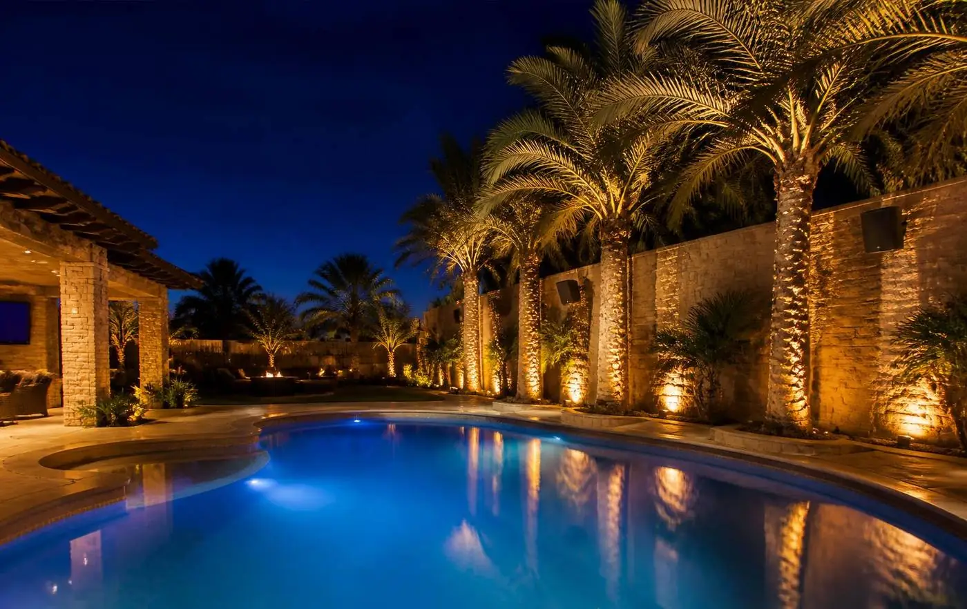 Luxury backyard with warm landscape lighting at night